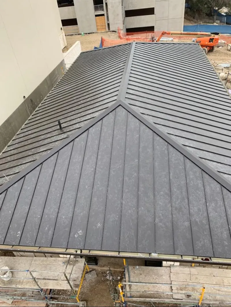 Commercial metal roof construction with crane equipment in Medford